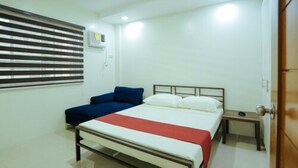 A bedroom with a bed, bedside table, and a window with blinds. - Ljenj Apartelle (Mabalacat City)