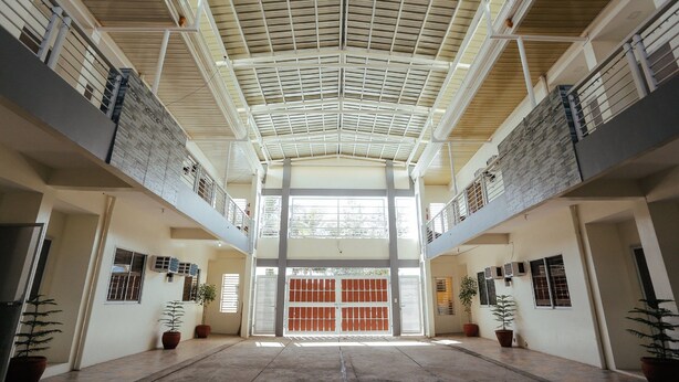 A spacious interior with a high ceiling, multiple floors, and potted plants. - Ljenj Apartelle (Mabalacat City)
