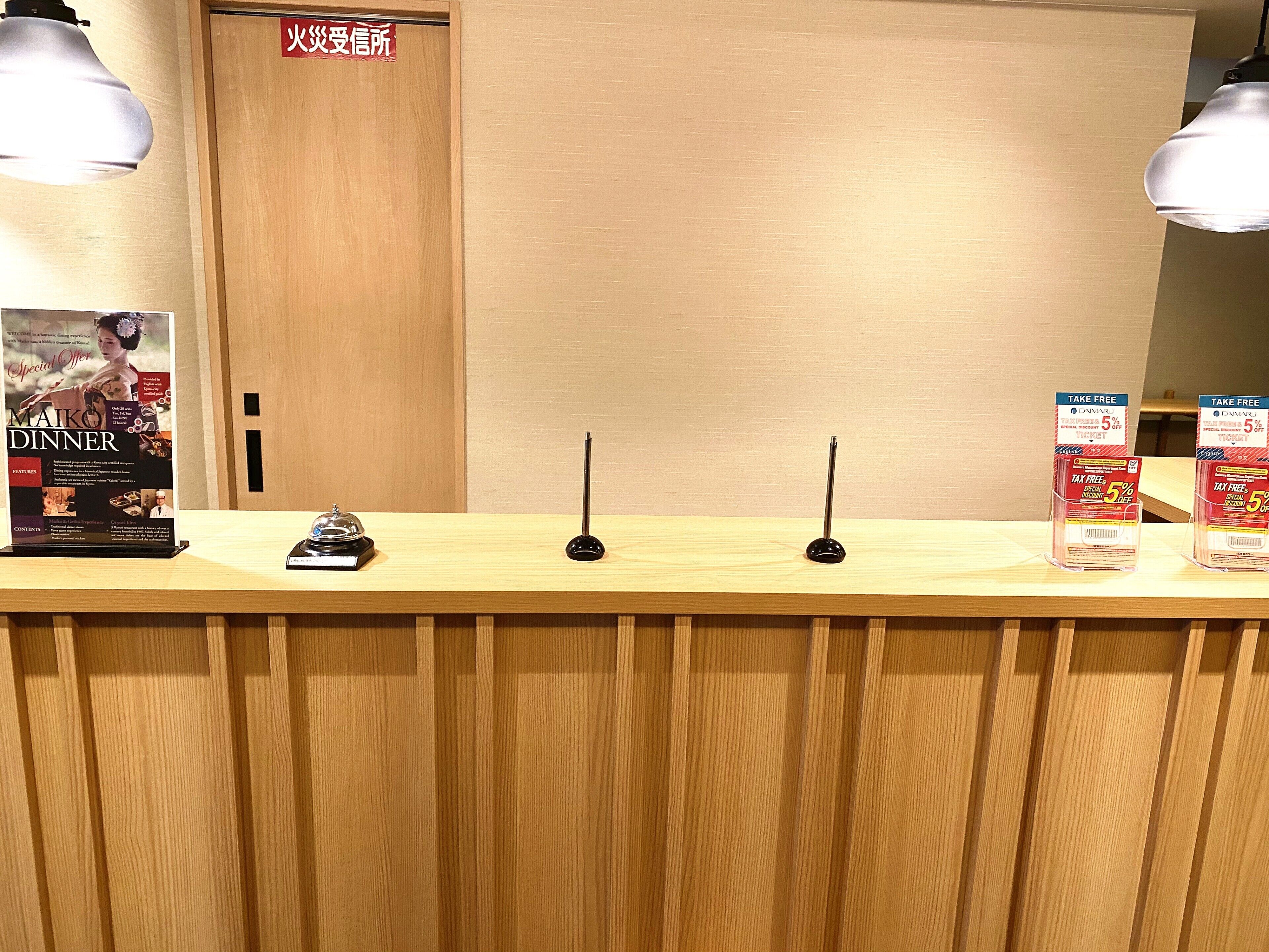 A wooden reception desk with a menu stand, two black telephone receivers, and a sign above the door.
