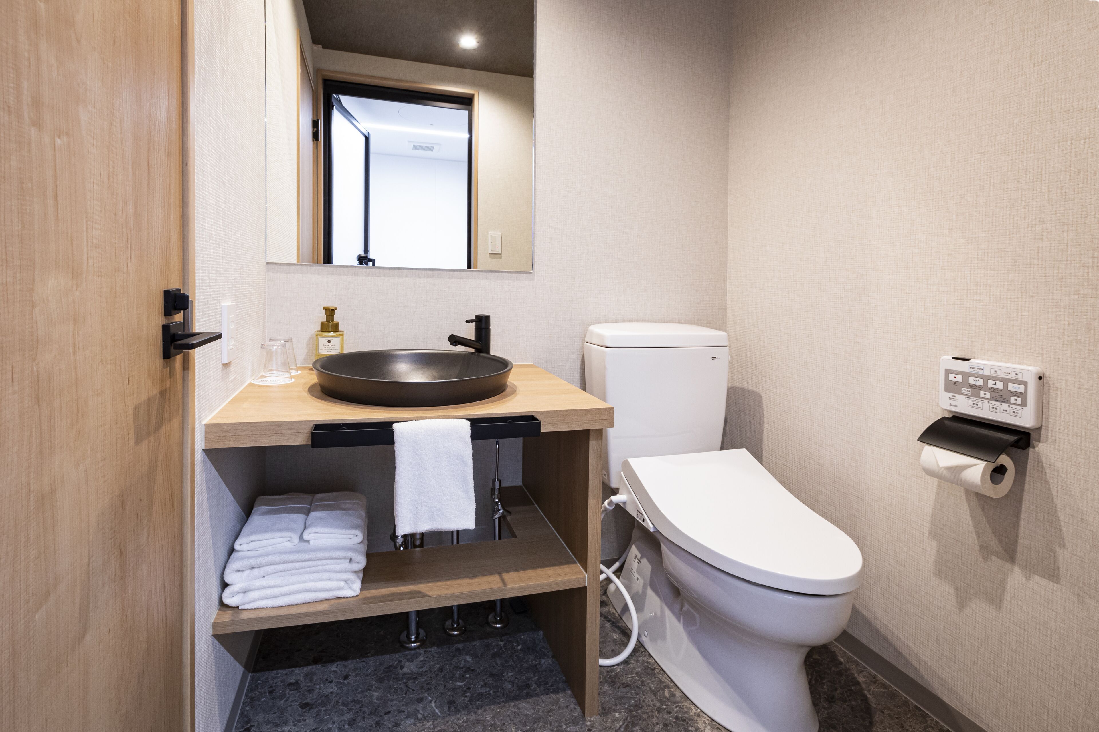 A modern bathroom with a wooden vanity, a sink, a toilet, and a towel rack.