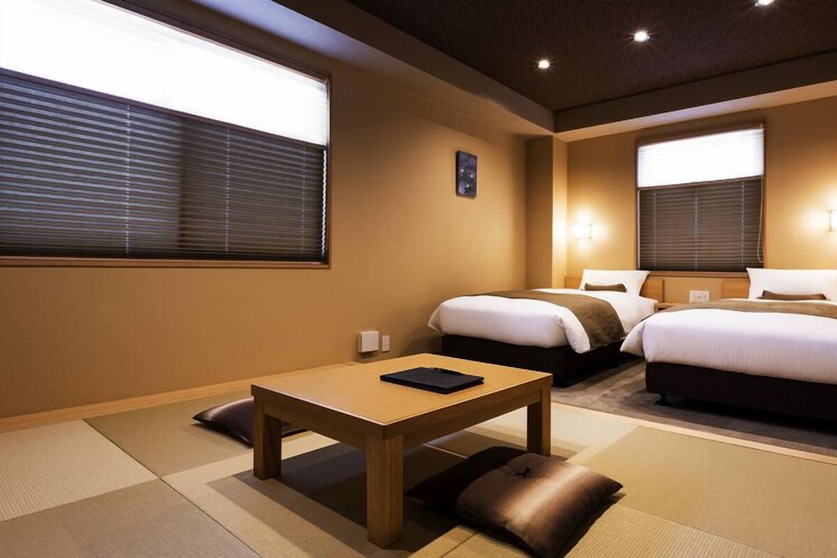 Habitació d'hotel amb dos llits, una taula petita i un futó.
