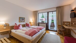 Une chambre à coucher avec un lit en bois, un bureau, une chaise, un téléviseur et une fenêtre avec des rideaux.