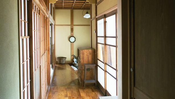 Un interior japonés tradicional con suelo de madera, puertas correderas y un ventilador de techo.