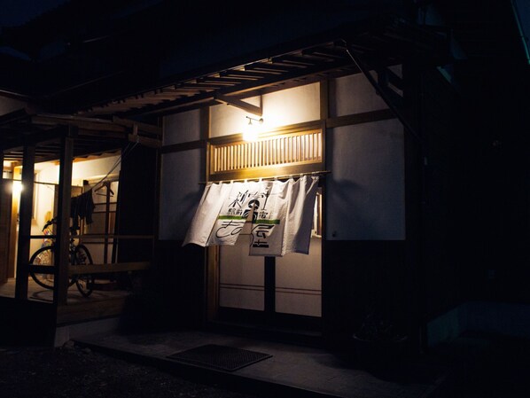 Un bâtiment japonais traditionnel, avec une structure en bois, un vélo garé à l’extérieur et une enseigne avec des caractères japonais.