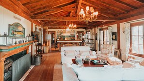 A cozy, rustic interior with wooden beams, a chandelier, and a dining area with a piano. - The Lake House (Orhangazi)