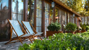 A covered outdoor seating area with two white canvas chairs, wooden planters with green shrubs, and a wooden pergola with a hanging lantern. - The Lake House (Orhangazi)