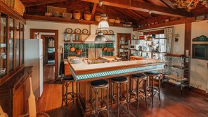 A spacious kitchen with a large island, wooden bar stools, and a rustic ceiling. - The Lake House (Orhangazi)