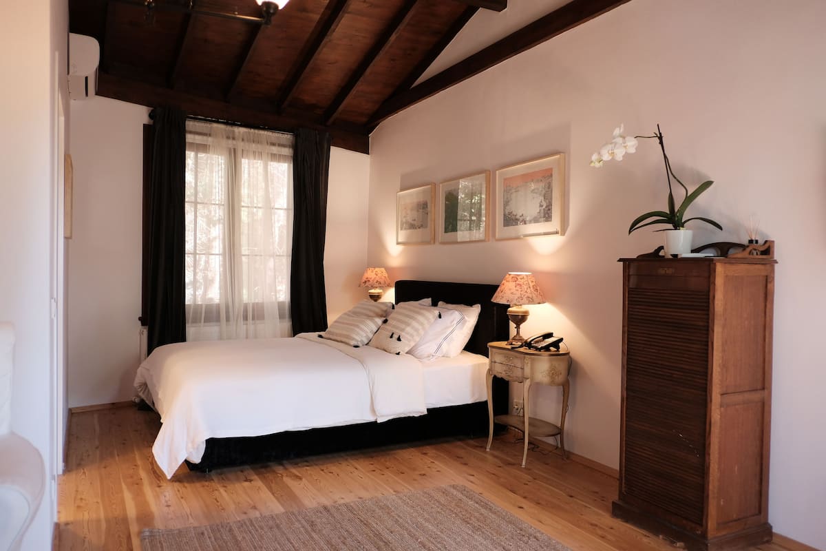 A bedroom with a bed, a nightstand, a wooden cabinet, and a window with curtains.