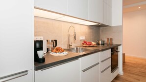 Una cocina moderna con armarios blancos, un lavamanos de acero inoxidable y un horno empotrado.