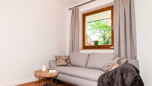 Una sala de estar moderna con un sofá gris, cojines estampados, una mesita de madera con una vela y una alfombra mullida negra.