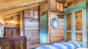 A wooden cabin interior with a bed, a green door, and a wooden dresser. - Holiday Home “Baita dai Cotai” in Fantastic Scenery with Mountain View (Porte di Rendena)