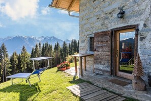 Un bâtiment en pierre avec une porte en bois, une petite table et une chaise à l’extérieur.