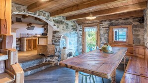 A rustic kitchen with stone walls, wooden beams, and a large wooden table. - Holiday Home “Baita dai Cotai” in Fantastic Scenery with Mountain View (Porte di Rendena)