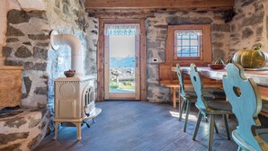 A rustic interior with stone walls, a wooden ceiling, a stove, and a dining area with chairs and a table. - Holiday Home “Baita dai Cotai” in Fantastic Scenery with Mountain View (Porte di Rendena)