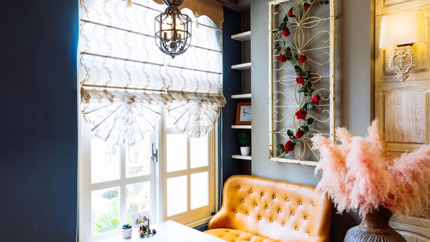 A cozy room with a wooden ceiling, a large window with curtains, a tufted sofa, a table, and a decorative vase. - Flower Young B&B (Hualien City)