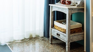 A room with a wooden side table holding a tray with cups and a blue pitcher, a woven basket, and a small drawer. - Flower Young B&B (Hualien City)