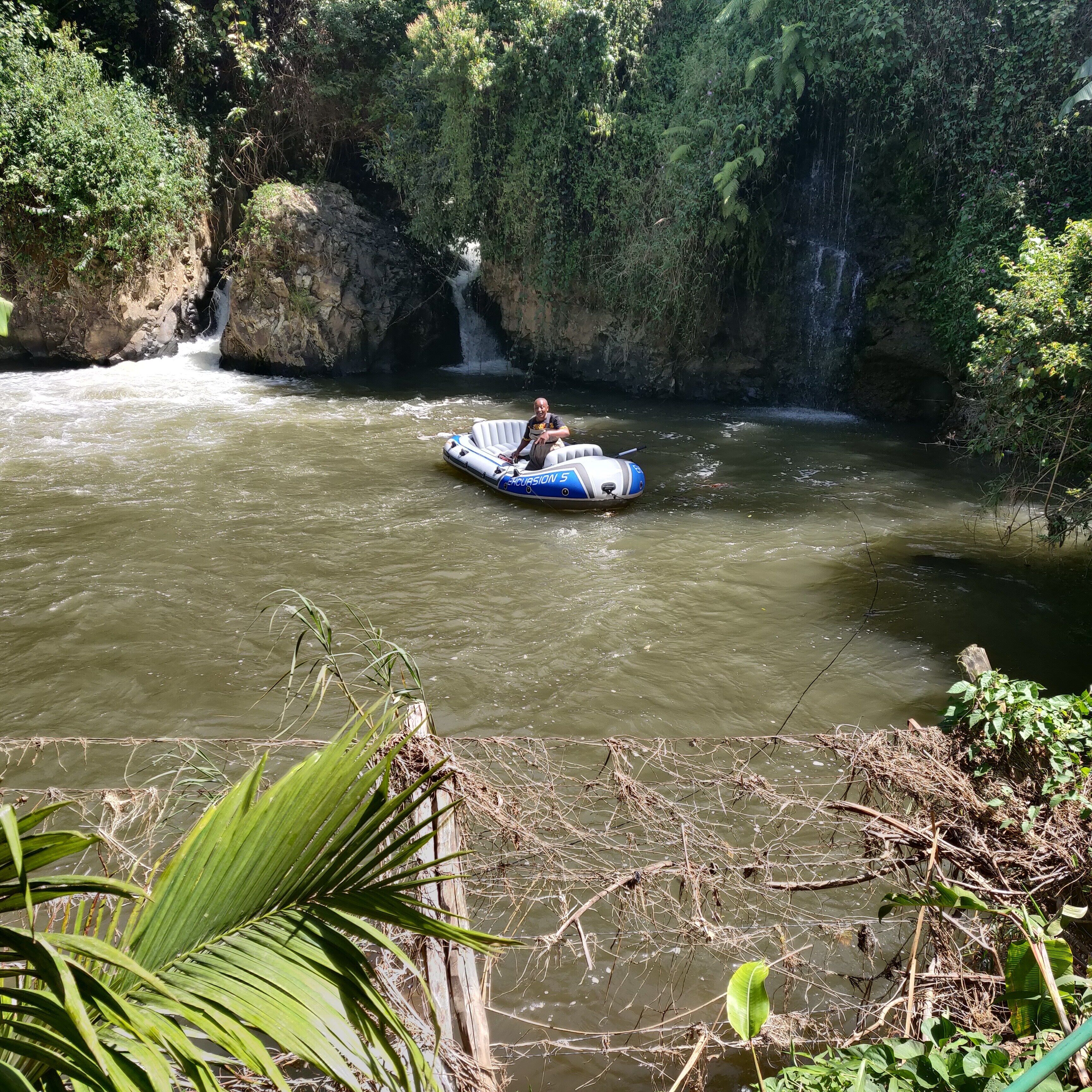 A river with a raft and a waterfall in the background.