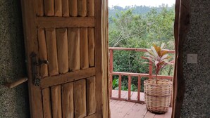Una porta in legno con il numero "202" che dà su un balcone con un cesto di vimini e un tappetino d'ingresso.