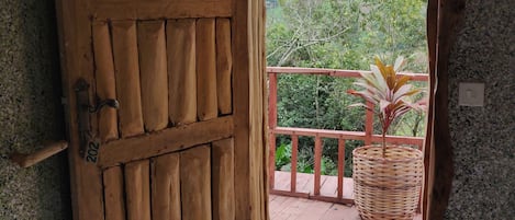 A wooden door with a number "202" on it, leading to a balcony with a wicker basket and a doormat.