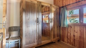 Een kamer met houten lambrisering, een grote garderobe, een kleine stoel en een raam met gordijnen.