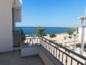 Un balcone con vista sul mare, arredi da esterno e cielo sereno.