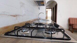 Una cocina con estufa a gas, lavamanos y piso de madera.