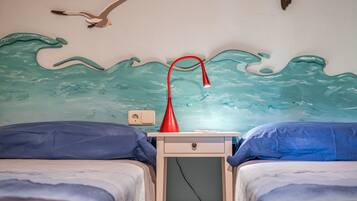 Une chambre avec deux lits, une table de chevet avec une lampe et une fresque murale.