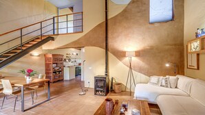 Un grand espace de vie comprenant un escalier, un canapé, une table basse et une cuisine en arrière-plan.