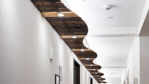 Un pasillo con techo de listones de madera, iluminación empotrada y piso alfombrado.