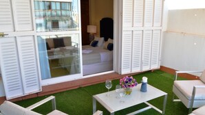 A hotel room with a balcony, a bed with white linens, a small table with a vase of flowers, and a chair. - Deluxe Penthouse Cathedral Views, 6 people, Parking optional (Sevilla)
