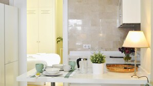 A hotel room with a bed, a bedside table with a lamp, a small potted plant, and a bathroom visible through an open door. - Deluxe Penthouse Cathedral Views, 6 people, Parking optional (Sevilla)