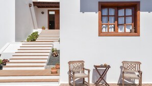 A white building with a wooden staircase, two wooden chairs, and a window with curtains. - Beautiful Villa La Petit with Pool, Terrace, Garden and Wi-Fi (GUATIZA)