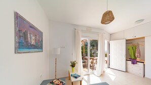 A modern room with a bed, a desk, a chair, a table with a vase, and a painting on the wall. - Sea & Sun (Rhodes)