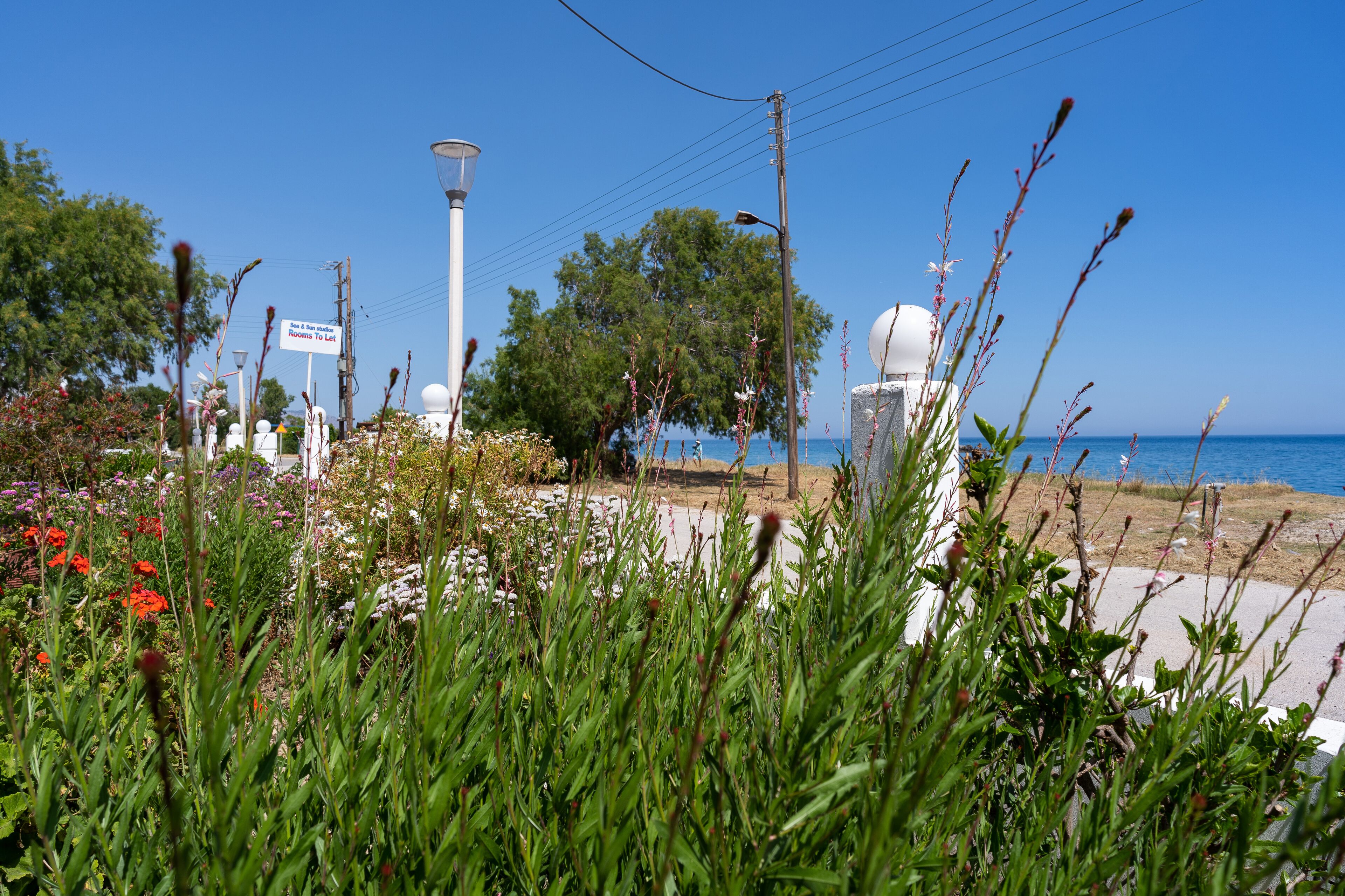 A coastal area with a clear view of the sea, a street lamp, and a signpost.
