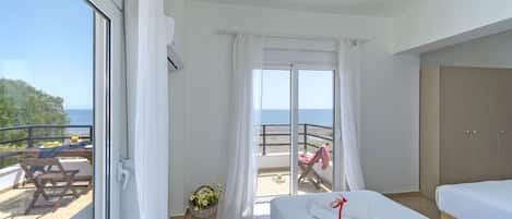 Ein Hotelzimmer mit Balkon, Bett, Schreibtisch und Meerblick.