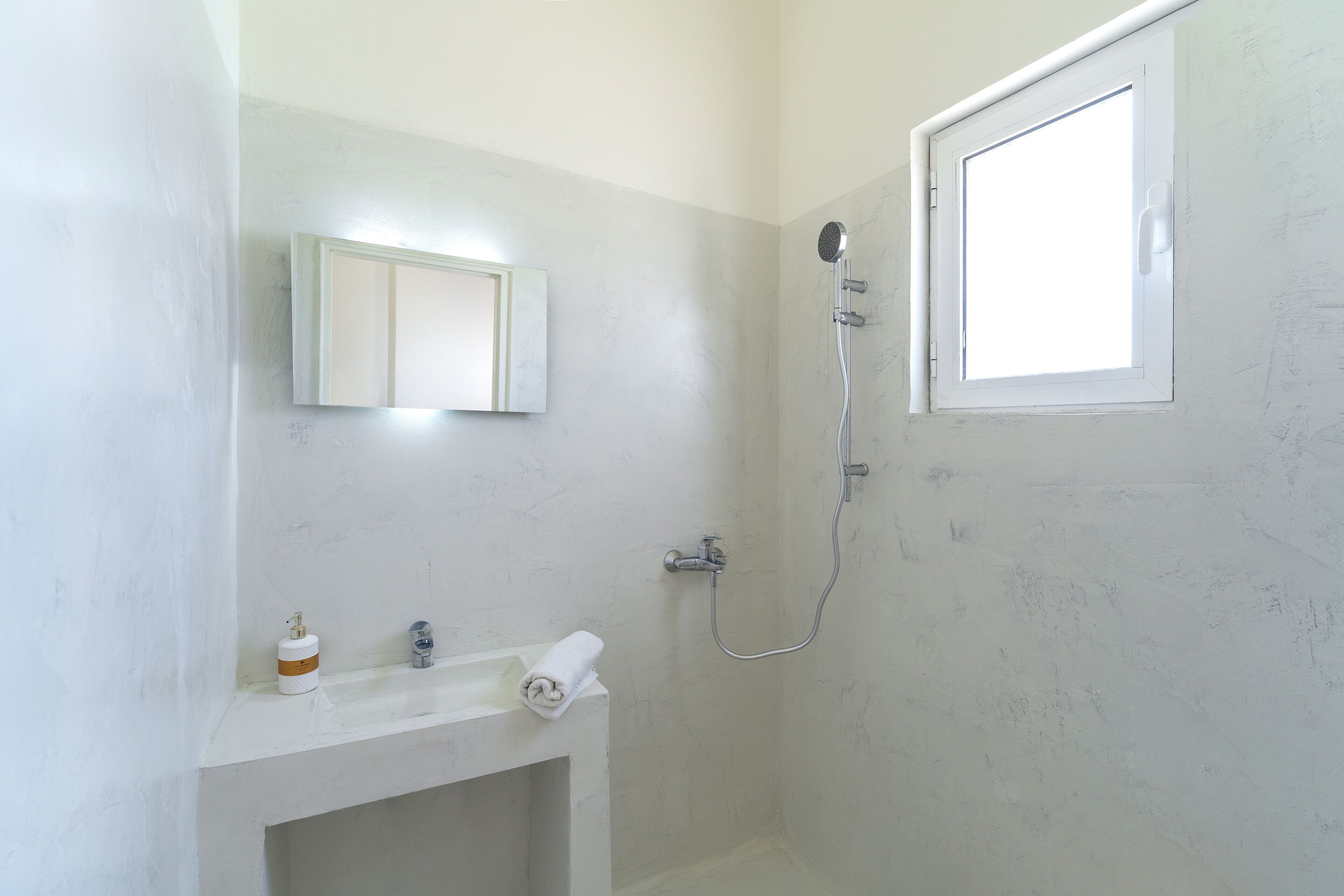 A bathroom with a white sink, a mirror, a towel, and a shower.
