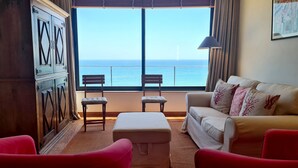 A room with a view of the sea, a sofa, two chairs, a small table, and a lamp. - Albufeira Beach Cliffs House by Rentals in Algarve (Albufeira)