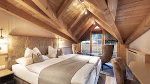 A cozy bedroom with a large bed, a wooden ceiling, and a window with a view.