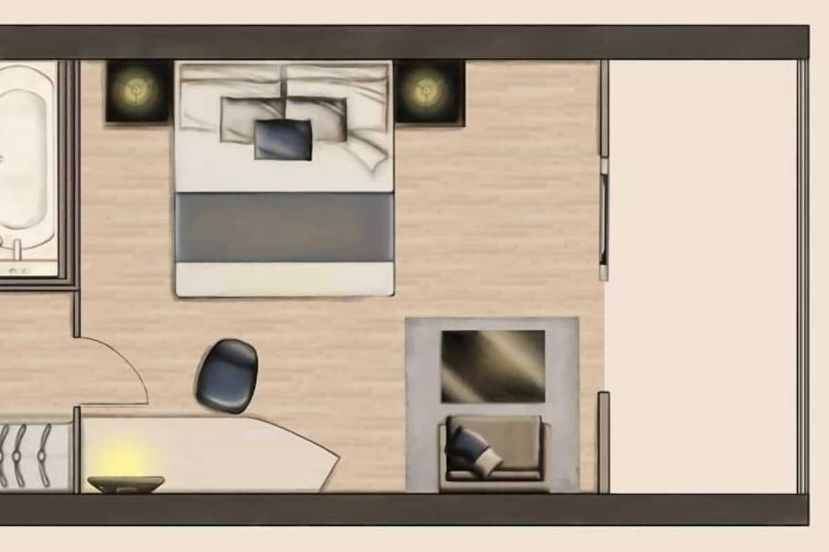 Planta baixa de um quarto de hotel com banheiro, cama, escrivaninha e área de estar.