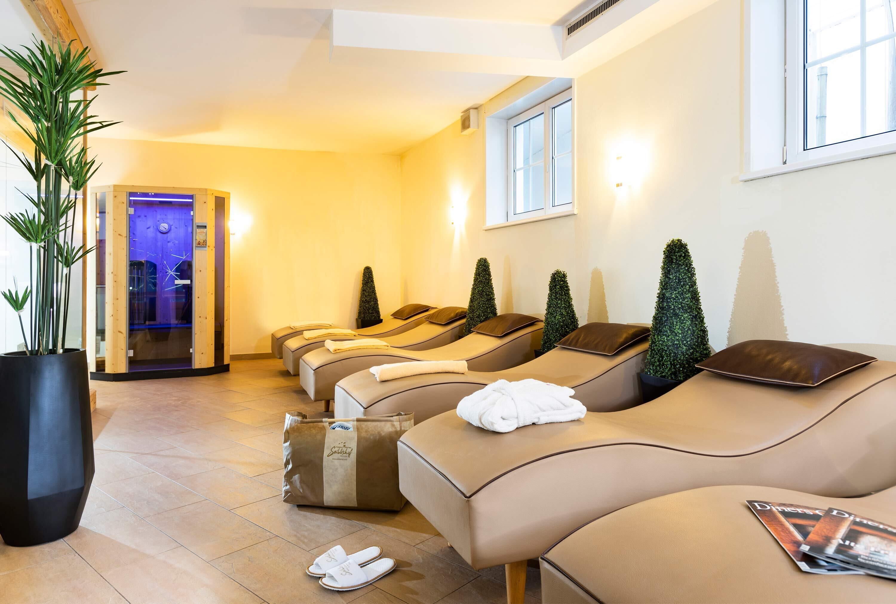 A spa room with multiple massage chairs, a large potted plant, and a window with natural light.