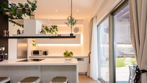 A modern kitchen with a central island, built-in appliances, and a view of the outdoor garden. - Feyre Boutique Mansion-Echoes of the Sea by etouri (Rethymno)