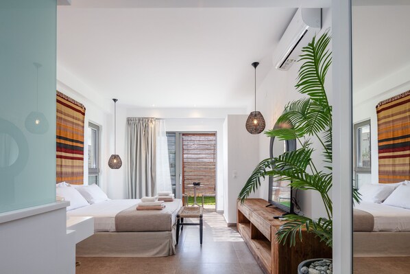 Ein modernes, helles Wohnzimmer mit einer Couch, einem Couchtisch und einem Fernseher. Ein großes Fenster mit Vorhängen, eine Pflanze und eine Holzbank sind ebenfalls vorhanden.