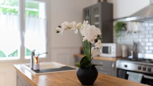 A kitchen with a wooden countertop, a black vase with white flowers, and a microwave.