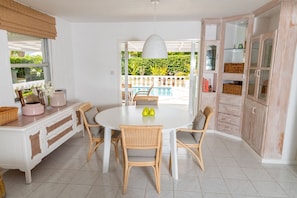 Un coin repas avec une table ronde, des chaises en osier et un buffet blanc doté de portes en verre.
