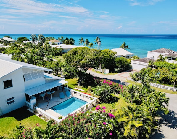 Zona residencial con piscina, abundante vegetación y vista al océano.