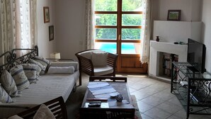 Een kamer met een bed, een stoel, een tafel, een open haard en een televisie.