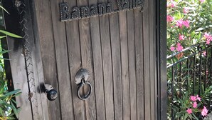 Een houten poort met de aanduiding ‘Banana Valley’ en een decoratieve metalen bovenkant.