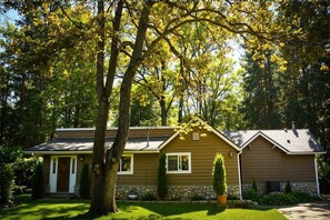 A single-story house with a stone foundation, a front porch, and a well-maintained lawn.