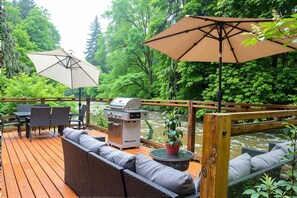An outdoor deck with a grill, seating area, and umbrellas.