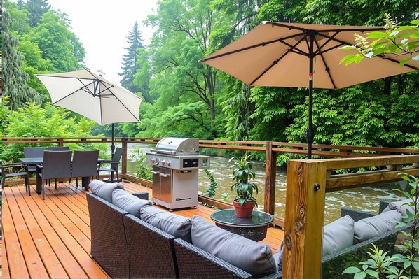 An outdoor deck with a grill, seating area, and umbrellas.